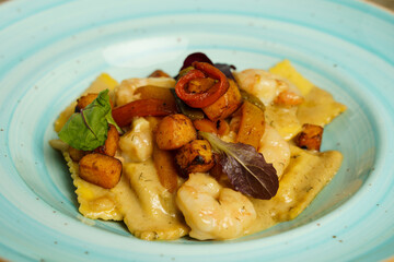 Plate of ravioli with shrimp in sour cream on a wooden table