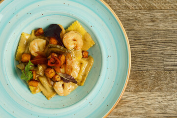Plate of ravioli with shrimp in sour cream on a wooden table