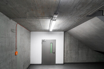 Concrete staircase in an office building. White wall with a door. Stairs and escape route.