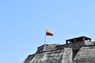 Bandera de Colombia en lo alto del Castillo de San Felipe de Barajas. Cartagena de Indias, Colombia. - obrazy, fototapety, plakaty