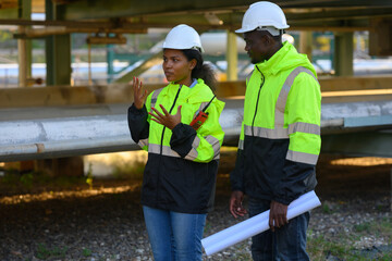 Male and female engineers check the drawing system inspection with the real pipe system of the new...