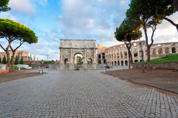Arch of Constantine and Colosseum with empty alley road, antique Rome city, Italy