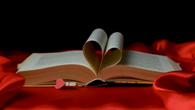 The pages of the book are folded in the shape of a heart on a red and black background. Love for books.