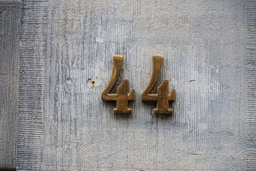 Closeup of metallic number 44 on stoned wall of building - 753744270