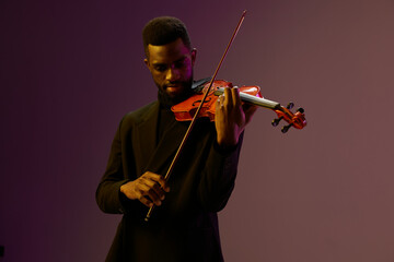 Elegant violinist in black suit performing classical music on purple background, creative musical...