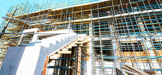 A building under construction with scaffolding and a staircase. The building is in the process of being built and is not yet finished