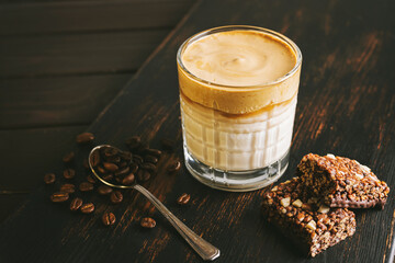 Dalgona coffee drink, cocktail with whipped instant coffee and milk in a glass on a wooden board...