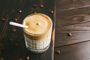 Dalgona coffee drink, cocktail with whipped instant coffee and milk in a glass on a wooden board