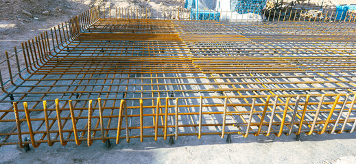 A metal fence is made of iron and is in a field. The fence is made of many pieces of metal and is very long