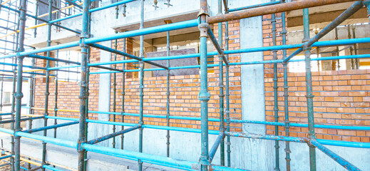 A scaffolding is set up in front of a building. The scaffolding is blue and yellow