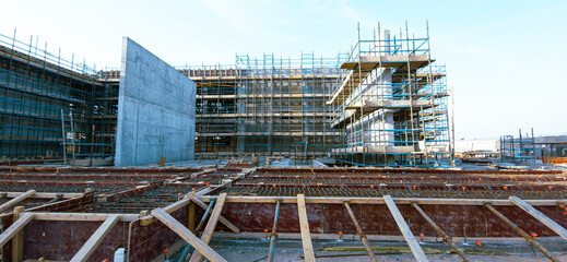 A construction site with scaffolding and a large building in the background. Scene is one of progress and hard work