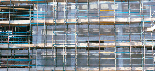 A building with scaffolding on it. The scaffolding is blue and yellow