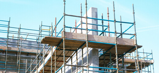 A construction site with scaffolding and a blue and white color scheme. Scene is that of a busy and active construction site