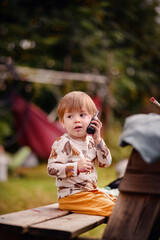 Toddler in Animal Print Shirt Talking on Toy Phone Outdoors