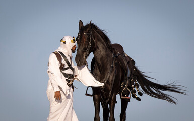 Rider in the desert of Saudi Arabia with his back stallion