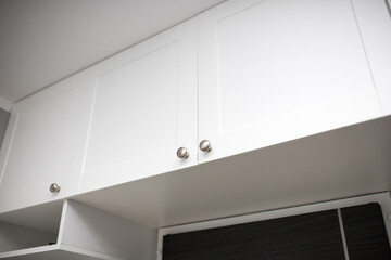 Cupboard under the ceiling above the front door. White cabinets lined above the entrance to the apartment.
