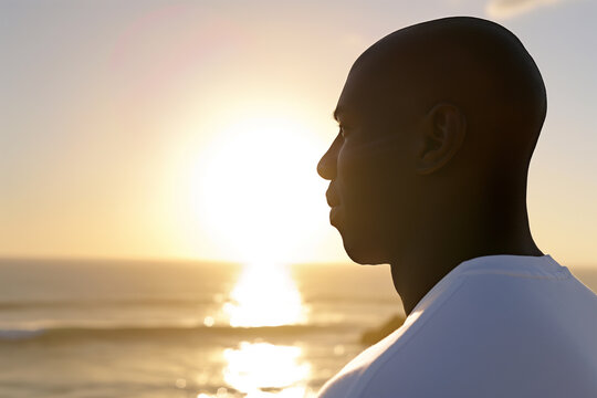 Serene sunset contemplation by the ocean featuring a pensive black man. View from the side
