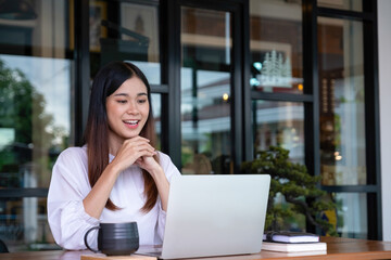 Young woman engages in online study or work at cafe.