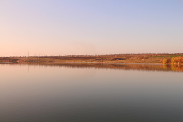 A body of water with grass and trees in the background