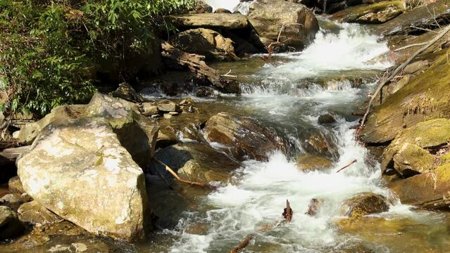footage of the rushing water, rocks and waterfall at Anna Ruby Falls with lush green trees and plants in Helen Georgia USA