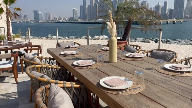 Dubai Jumeirah beach with marina skyscrapers in UAE. Luxurious sandy beach in the Dubai Marina area with views of the iconic skyscrapers. Beaches and Dubai eye view at sunset with boats and yachts.