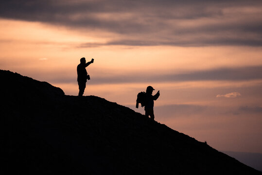 Two travelers silhouettes taking photos with their phones.