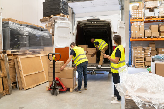 Teamwork At Logistic Centre. Unloading Delivery Van.