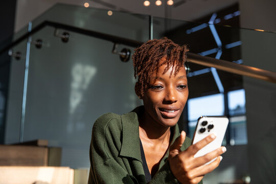 Woman Looks Intently At Her Phone While Sitting on Stairs