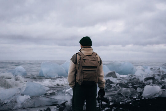 Man with camera, amid ice and glaciers under a cloudy sunset sky 