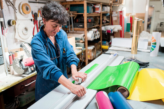 Happy mature worker cutting materials at workshop