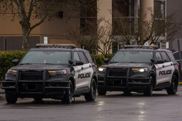 Police cruisers SUV responding to suspiscious activity in parking lot on rainy day