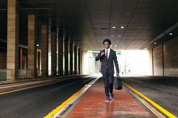 A well-dressed african businessman walks past a tram stop.