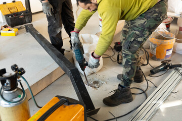 Construction worker drills a hole in the floor