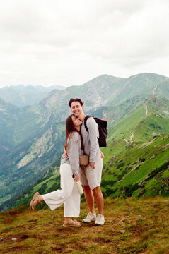 A man and a woman hugging and laughing on top of a mountain