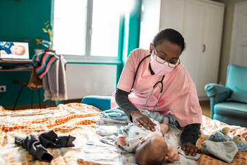 Pediatrician examining a baby at home