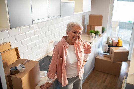 Smiling portrait of a senior woman at home with moving boxes around