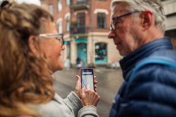 Senior couple using location app on smartphone together in the city