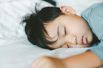 Fototapeta na wymiar Asian boy sleeping on white bed. New family, protection, relaxation and relationship concepts.