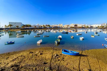 Papier Peint photo les îles Canaries Colorful small fishing boats float in the Charco de San Gines seawater lagoon at the seaside Spanish town of Arrecife, Spain, on Lanzarote Island, one of the Canary Islands in the Atlantic Ocean.