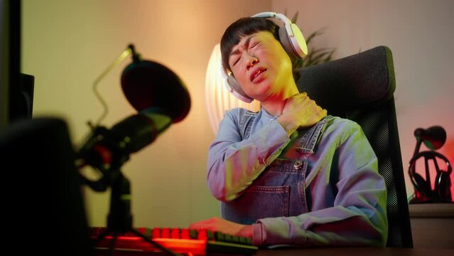 Beautiful asian woman gamer suffering from neck pain while have live stream season, 4k video footage. People, healthcare and problem concept - unhappy woman suffering from neck or shoulder pain 