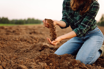 Farmer woman holding soil in hands close-up. Cultivated dirt, earth, ground, brown land background, nature.