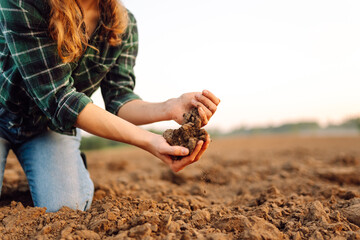 Farmer woman holding soil in hands close-up. Cultivated dirt, earth, ground, brown land background, nature.