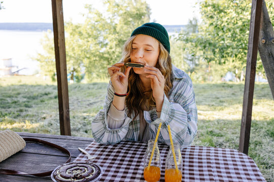 Woman playing harmonica sitting at a picnic table 