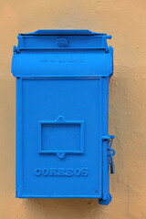 Blue painted vintage post box -buzon de correos- for the outgoing mail, padlock-closed, on a orange-ocher building wall. Old Havana-Cuba-057