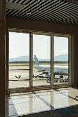 View of an airport boarding gate with a large window without people overlooking the runways of...