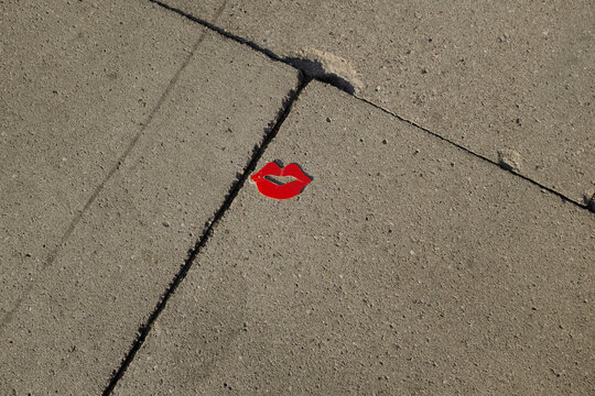 Red classic kiss lips-shaped piece of paper laying on a concrete floor