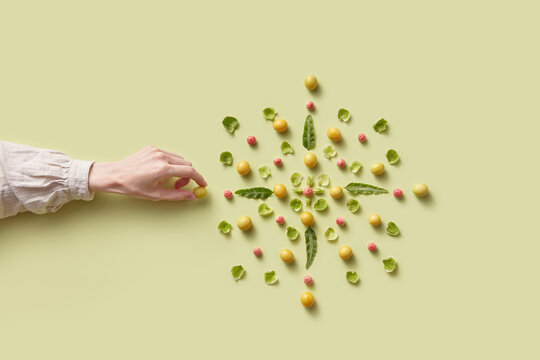Female hand adding cherry plum into mandala pattern
