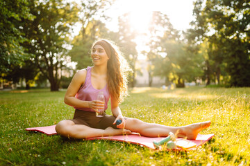 Young woman doing yoga, sports exercises in the park. Fitness. Active lifestyle.