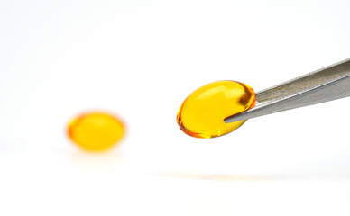 Fish oil,Omega-3,lecithin,DHA, Vitamins capsules is holding by metal chopsticks on white background. healthy supplements,extraction oil capsules