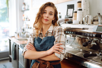 Young woman cafe owner in an apron looks at the camera and smiles. Business concept. Food and drink concept.